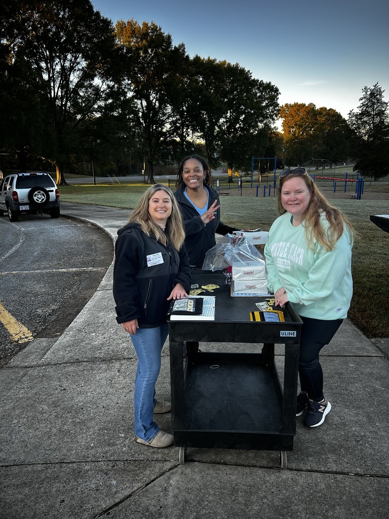 Three ladies stand at black cart full of donuts