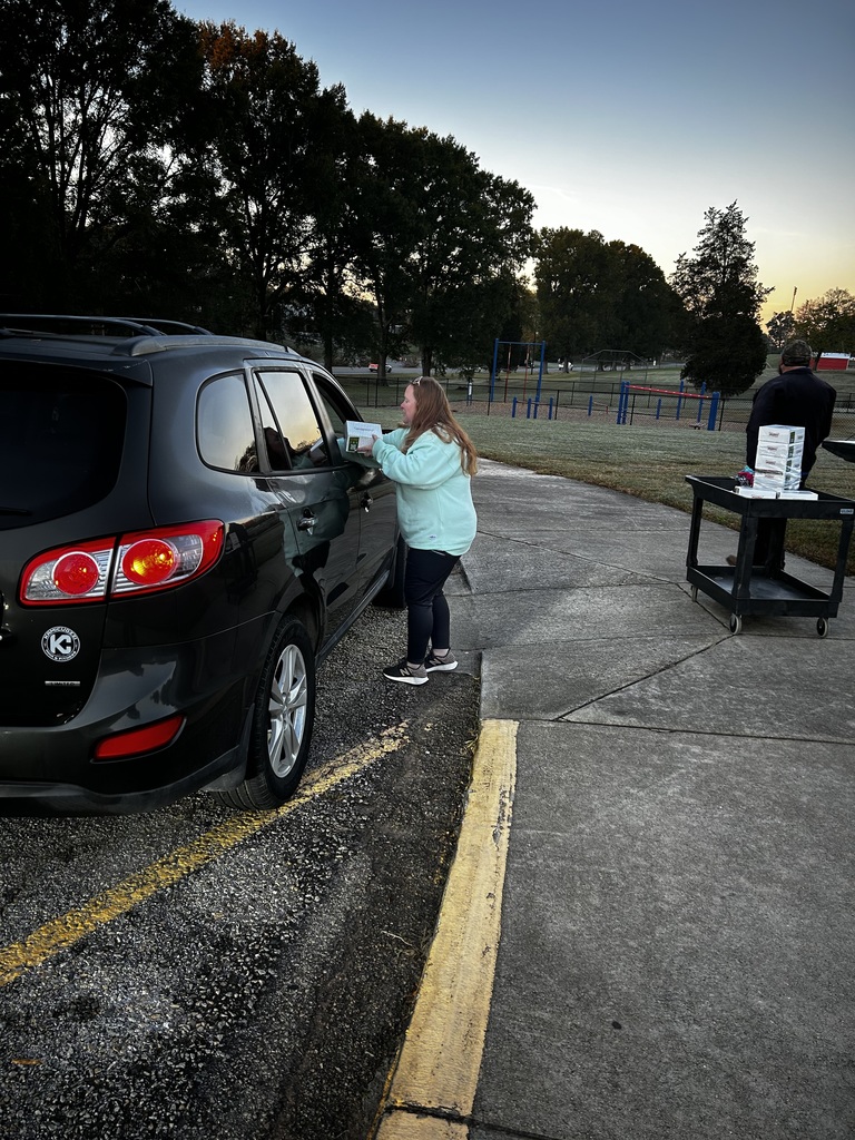 Parent leans over into car handing them a dozen donuts