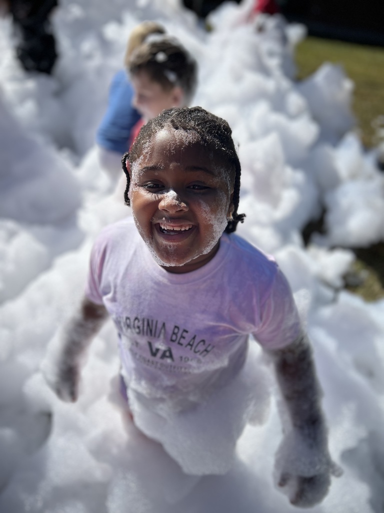African American female stands in white foam. It's covering her cheek, arms, and lower half of her body.