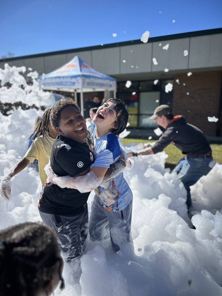 two male students are seen hugging while standing in foam