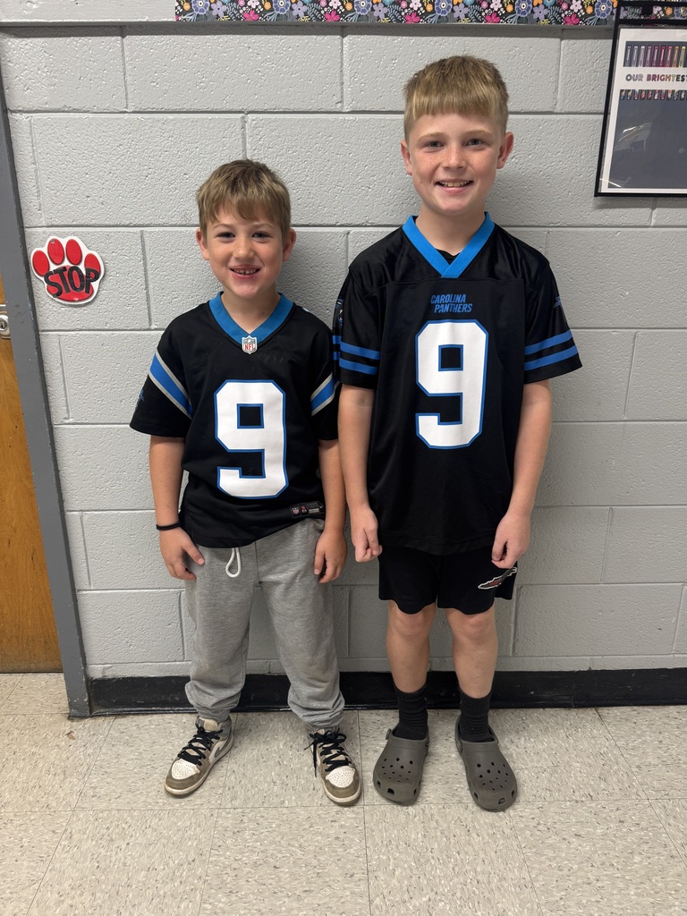 two boys stand wearing black Carolina Panthers jerseys with the number 9 displayed on the front. 