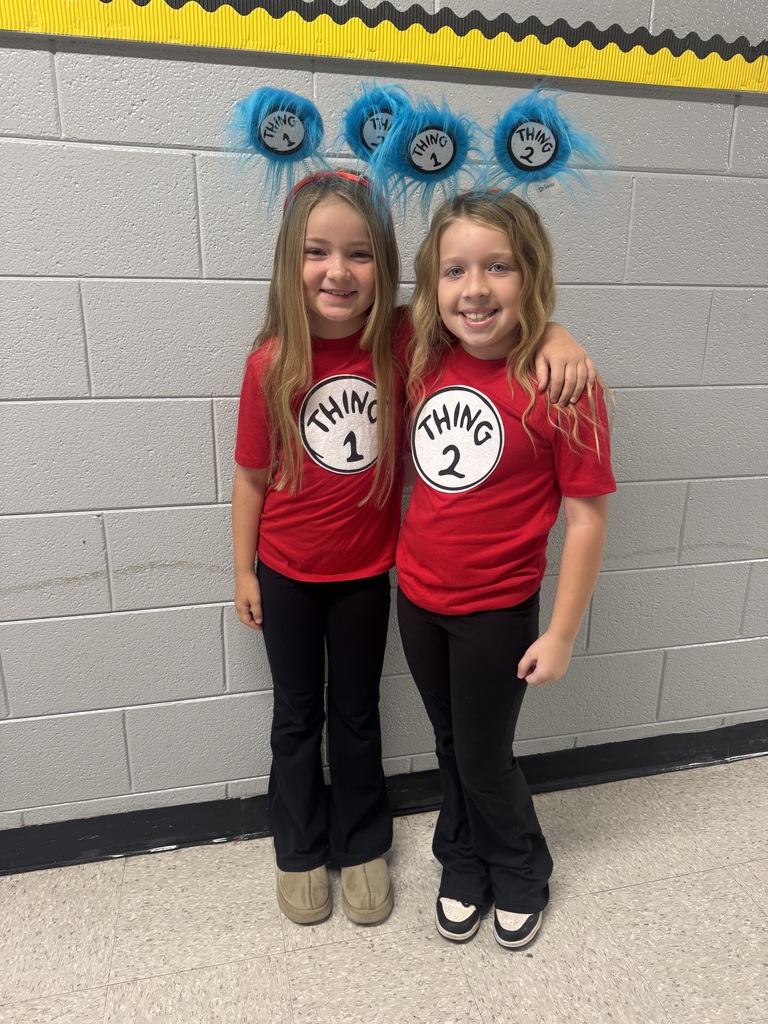 two girls stand together with arms around each other wearing a blue Dr. Seuss headband, a red thing 1 and thing 2 shirt, and black leggings. 