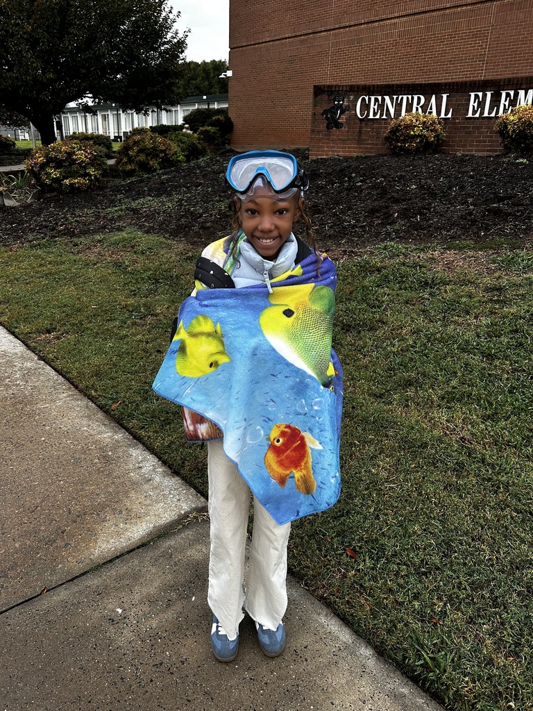 Student wears goggles on head and is wrapped in beach towel. 