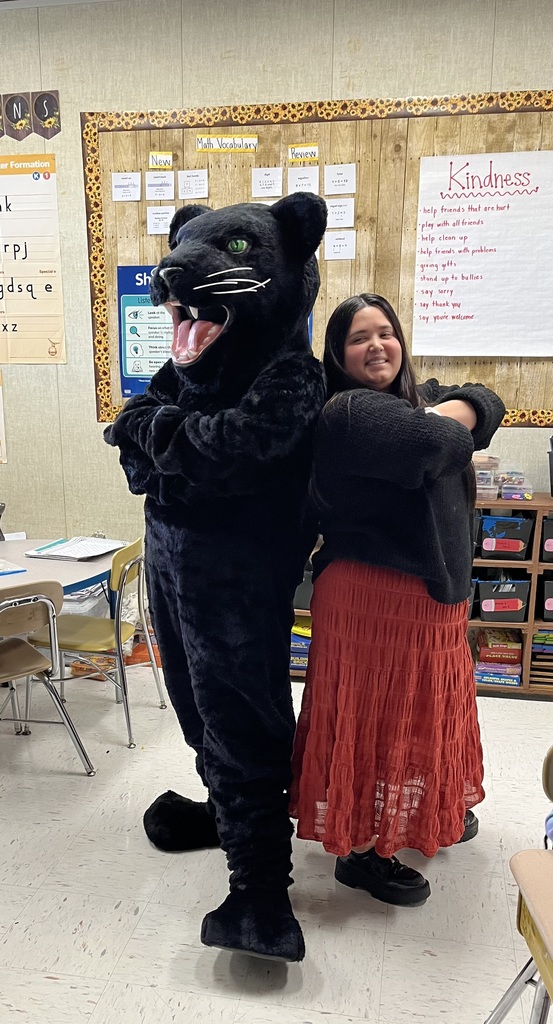 The teacher stands back to back with the black panther cub mascot. 