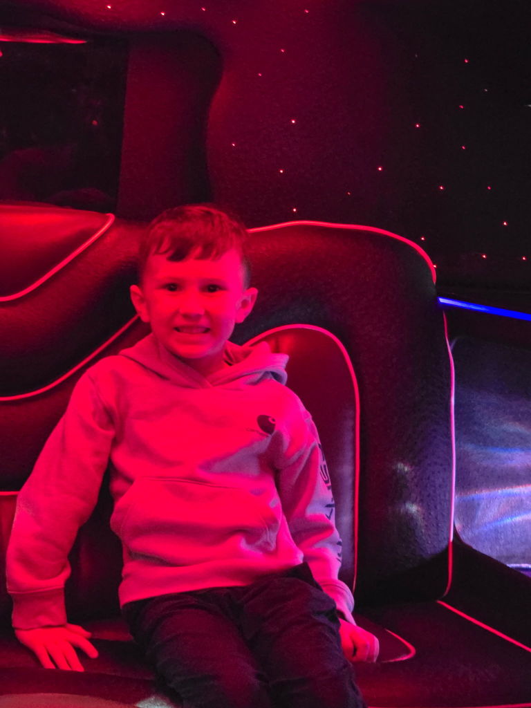 Boy sits in limo and is illuminated by red light. 