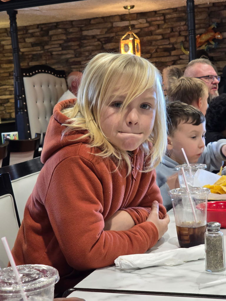 boy sits inside of restaurant leaning on table