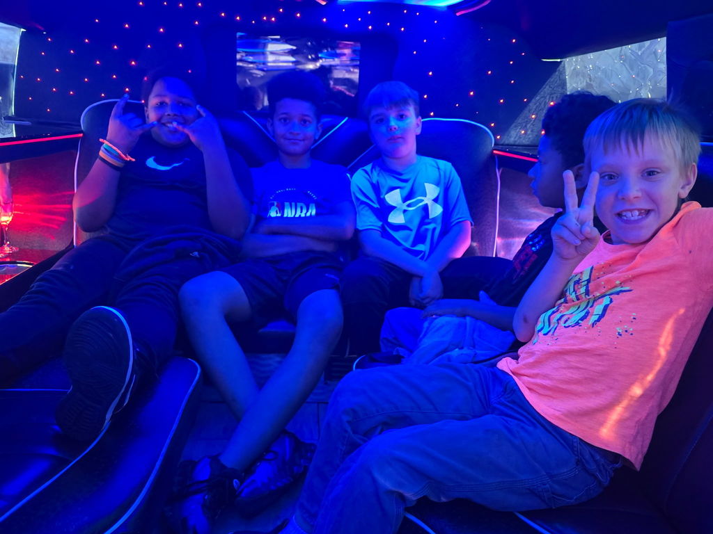five boys sit together in back of limosuine and are illiminated by glow lights