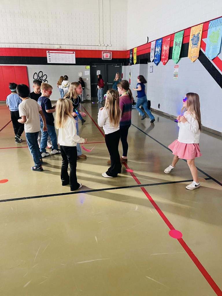 a group of students are seen standing together dancing in the gym 