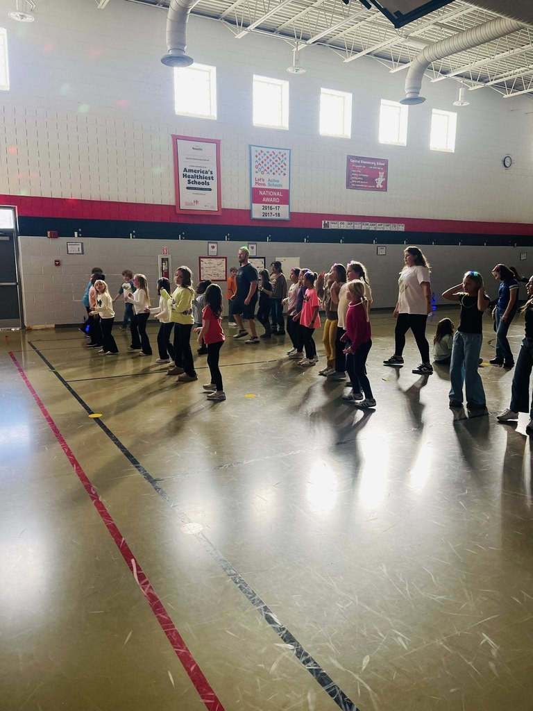 A group of students dance together in the dark gym 