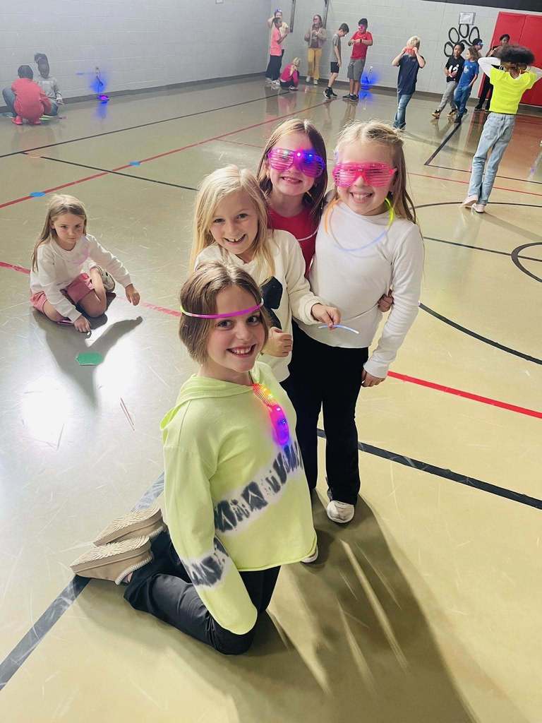 four girls smile together with their glow in the dark necklaces and sunglasses