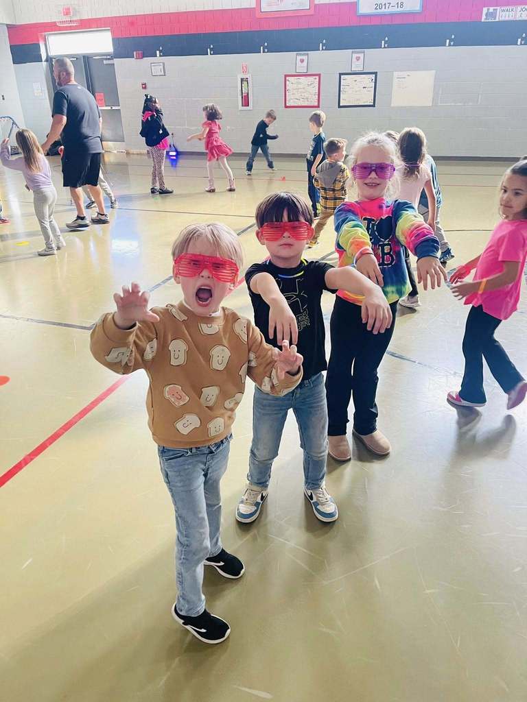 two boys and a girl stand with their light up sunglasses pretending to do the Thriller dance