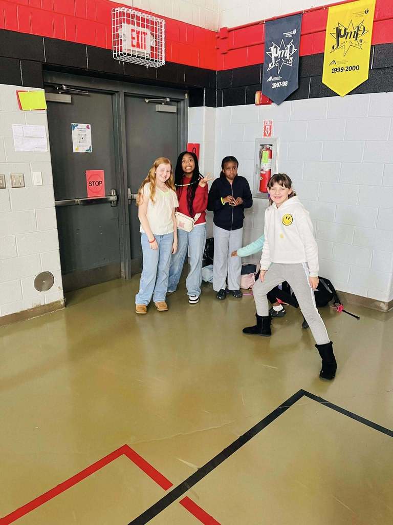 Four girls stand together near gym door