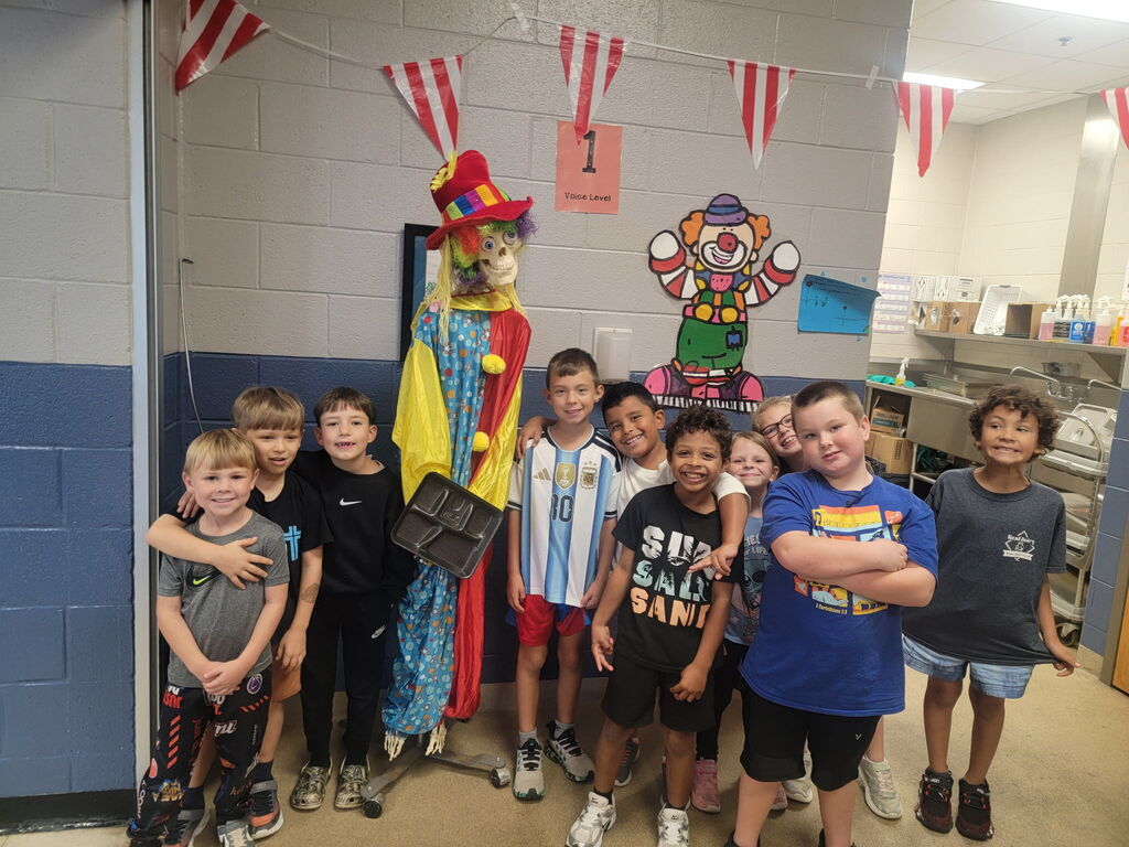 National School Lunch Week 2026- Ten students standing in front of a skeleton decoration dressed as a clown inside their lunch room