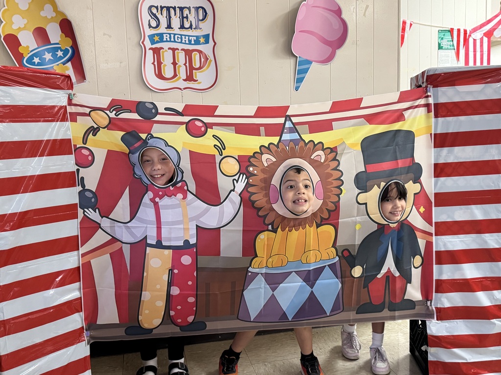 National School Lunch Week 2026- Three students with their faces inside a circus theme photo op depicting a juggling clown, lion on a pedestal and a ring leader