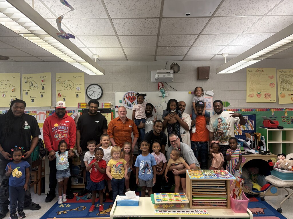 Fathers join students in Reidsville Elementary's Head Start 1 & 2 classrooms. They're posed as a group together in the middle of the classroom. 15 students and 10 dads are pictured.