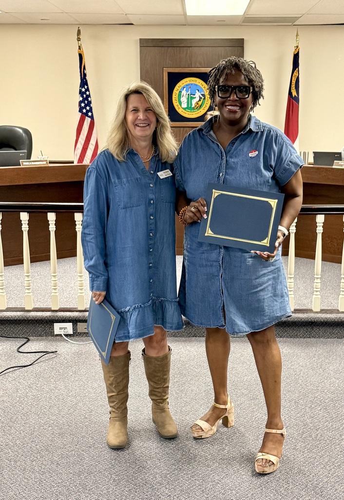 Rockingham Co Schools Board of Education member Paula Rakestraw and Valencia Abbott smile while posing in the meeting room while holding their recognitions for the Long Leaf Pine Award