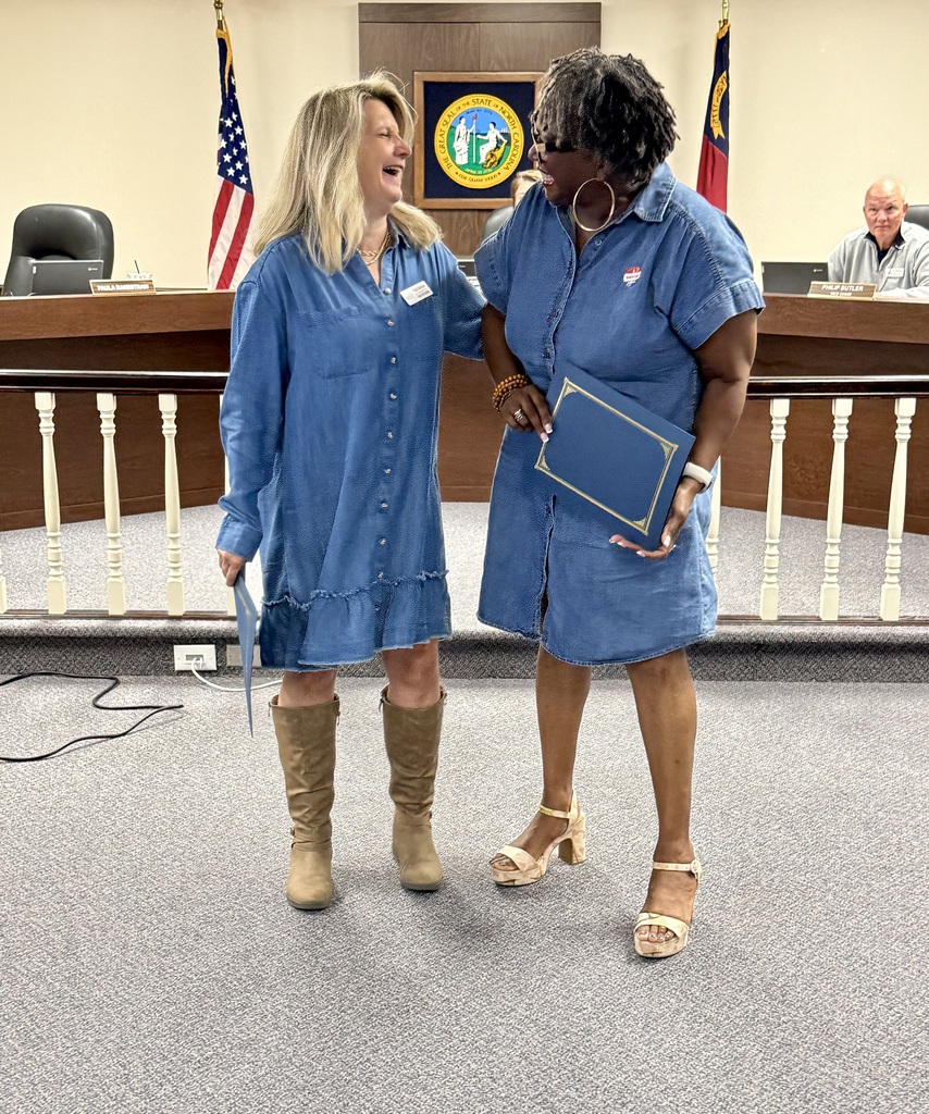 Rockingham Co Schools Board of Education member Paula Rakestraw and Valencia Abbott laugh while posing in the meeting room while holding their recognitions for the Long Leaf Pine Award