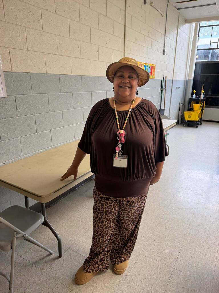 Red Ribbon Week- Central Elementary Hat Day: Teacher posed next to a table wearing a sun hat