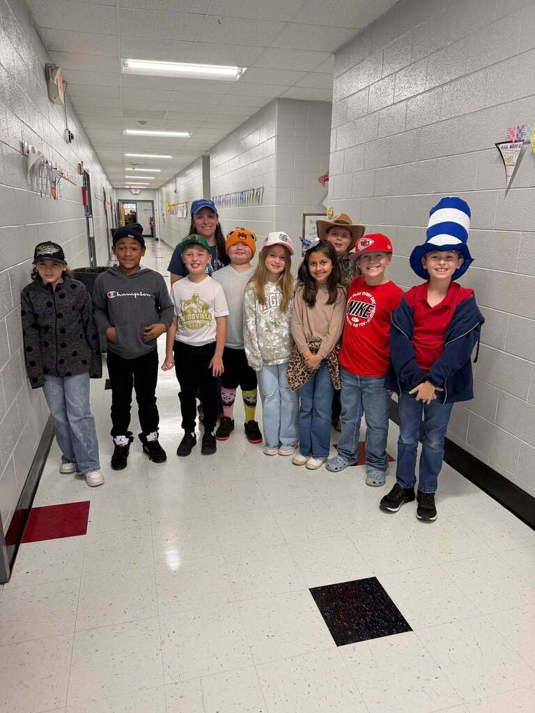 Red Ribbon Week- Central Elementary Hat Day: 9 students and a female teacher grouped together in the hallway while all wearing various style hats