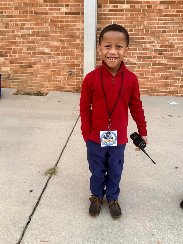Reidsville Elementary School Principals for a Day- Little boy standing outside wearing a red pullover and blue jeans and holding a walkie talkie and wearing a lanyard/name tag