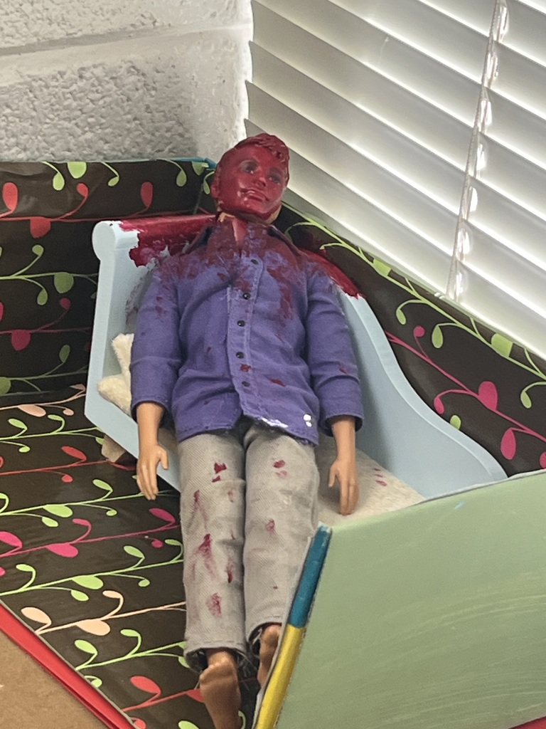 Rockingham County High School Public Safety class: A dummy laying on a couch, wearing a blue button up shirt and khakis, covered in fake blood
