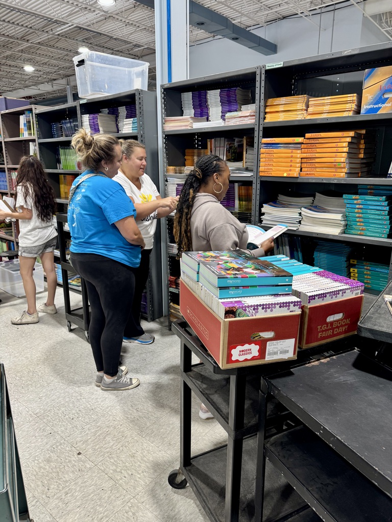 Four people in a bookstore, three standing and one sitting, surrounded by shelves filled with books.
