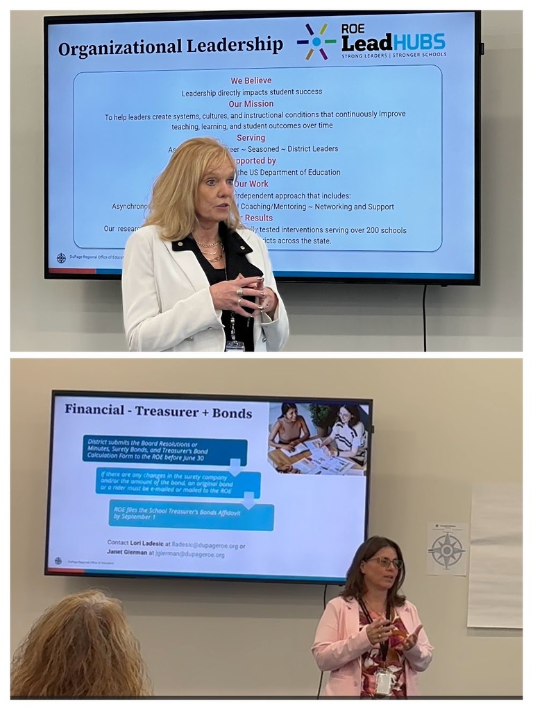 Two women in a room, one speaks into a microphone and the other stands by a screen. Behind them is a large screen displaying a slide with "Organizational Leadership" and text.