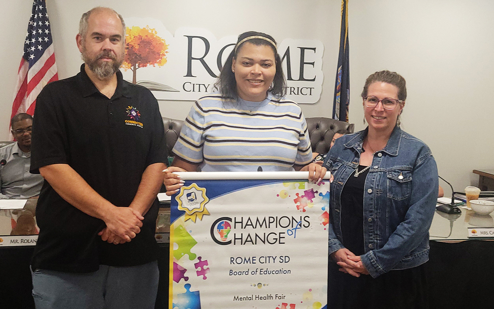 Representatives pose with the NYSSBA Champions of Change banner.
