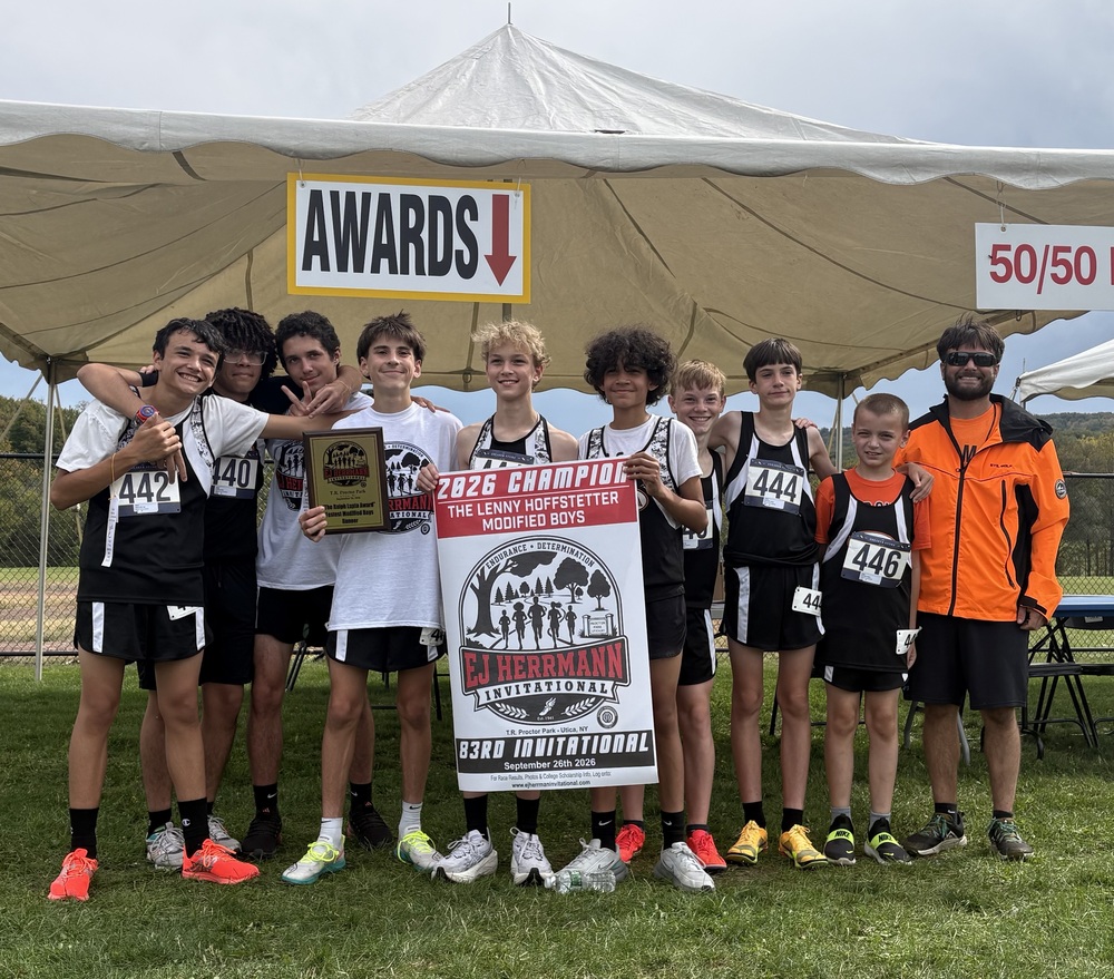 The cross country team poses for a team photo with their first-place banner.