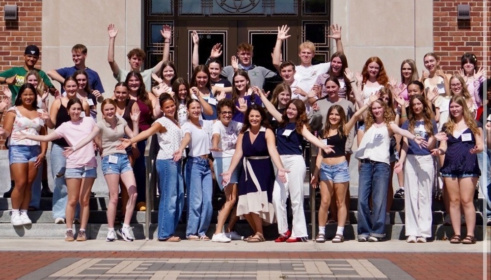 A group of students pose for a photo outside.