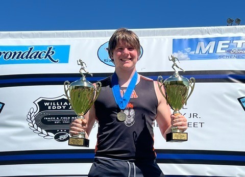 Rome Free Academy junior Jacob Ciccone poses on the podium while holding two first-place trophies.