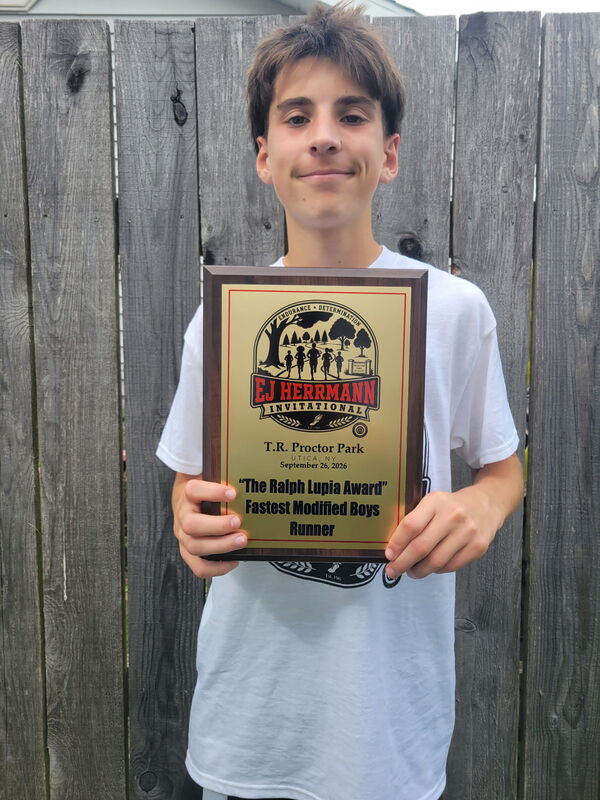 A cross country runner holds their first-place plaque.