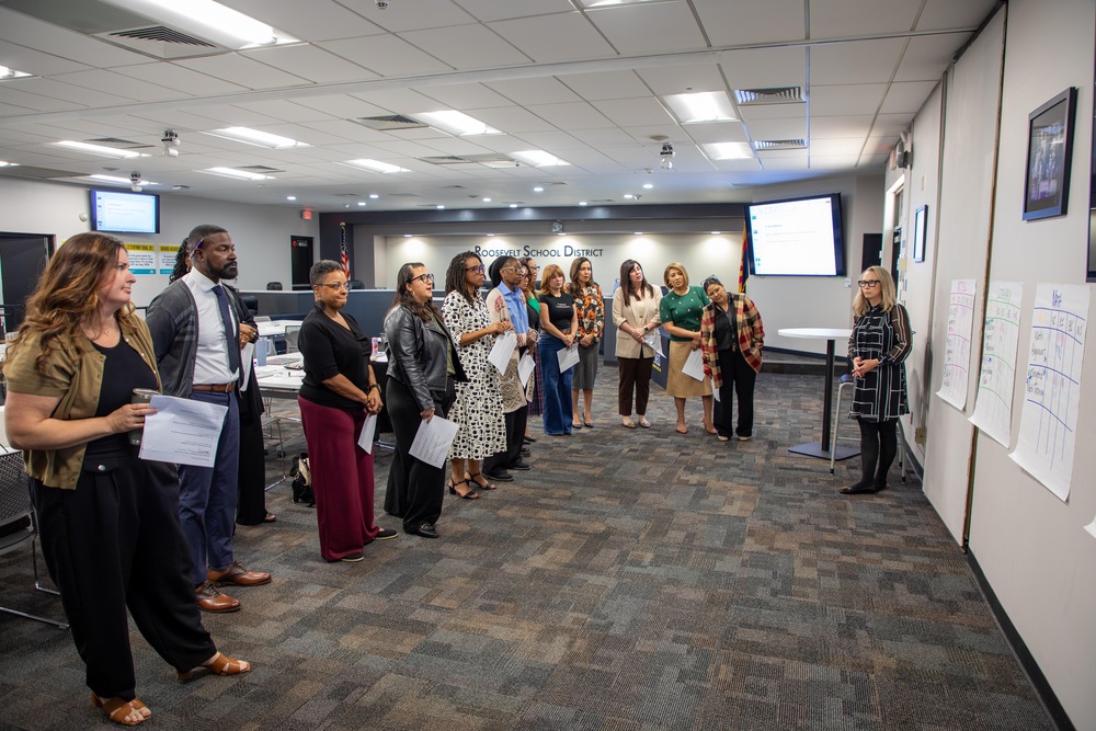 Group of adults standing listening to a presentation