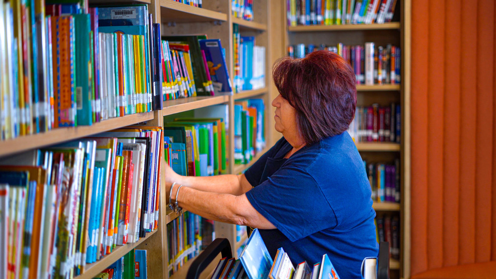 A paraprofessional re-shelves library books