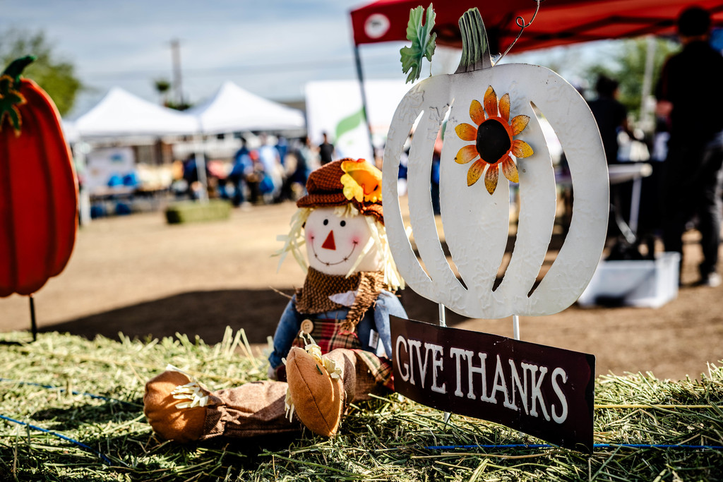 image of a haystack with a metal pumpkin.  There are tents in the background