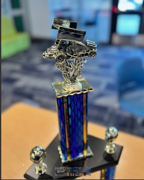 blue trophy with a gold car on top resembling the esports car from the championship game.