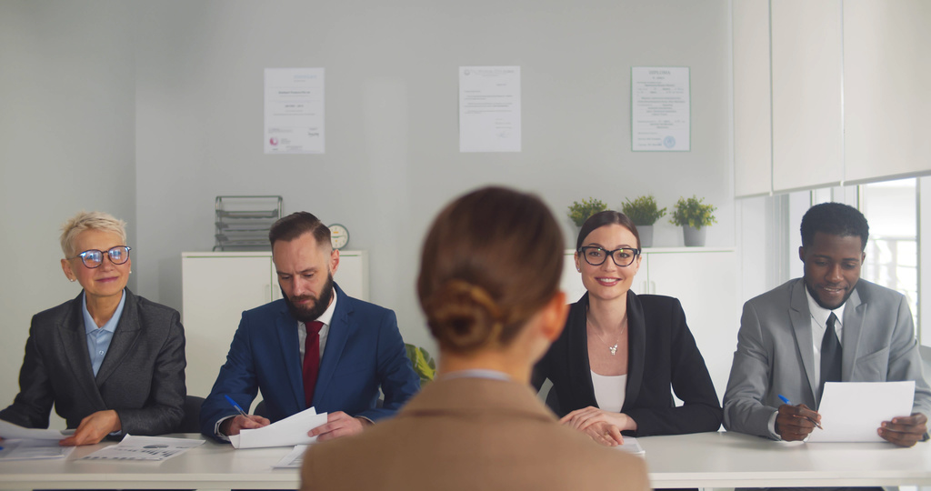 An interview candidate sitting in front of a panel of diverse employees