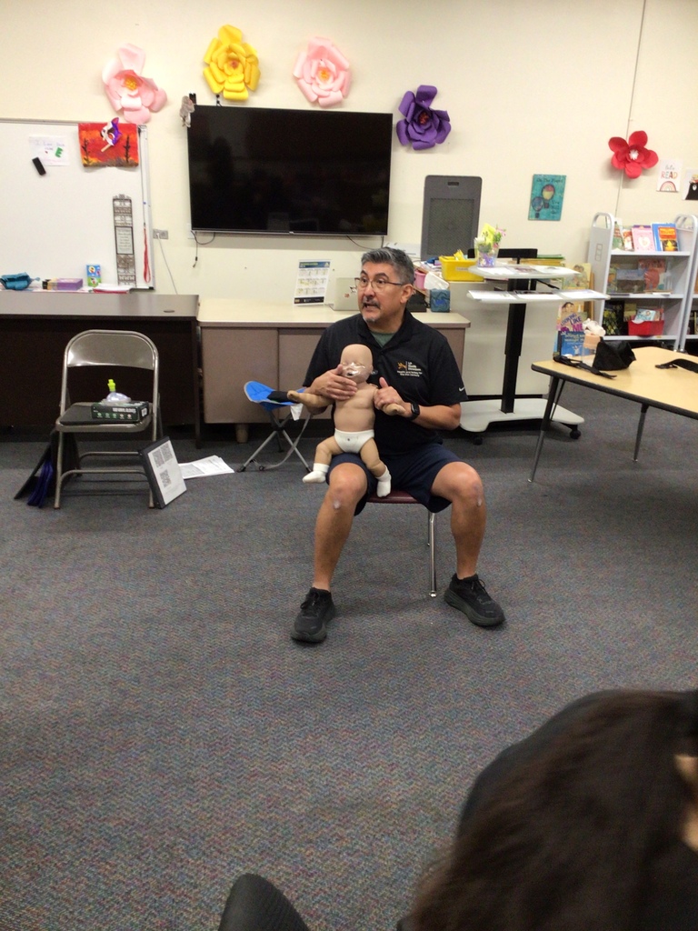 Adult male holding a baby mannequin to demonstrate how to help with choking.