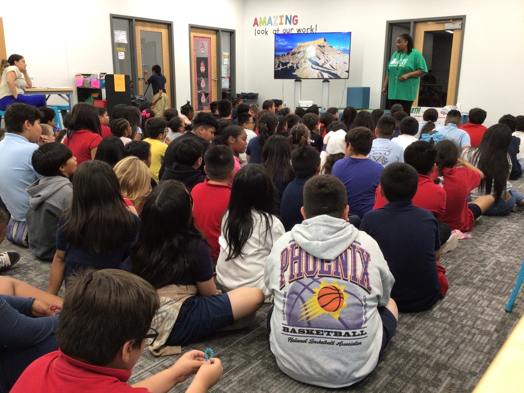 Students sitting on floor listening to librarian.