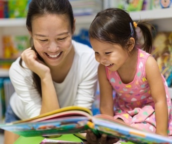  A mother and young daughter smile while looking at a colorful picture book together in a classroom. Thank you, and I’ll see everyone soon! 😊