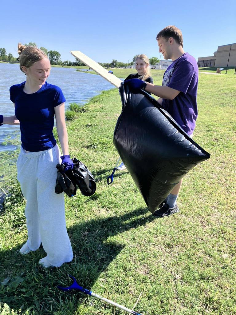 3 students cleaning up around the community pond for Earth Day