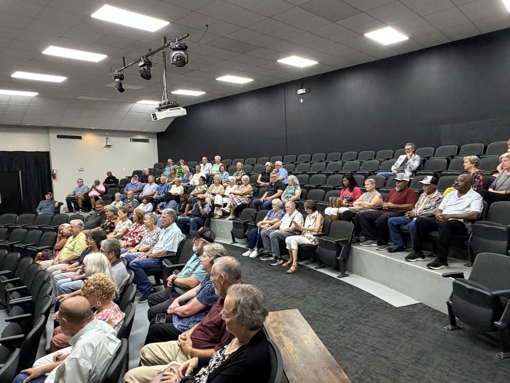 Audience sits listening to the speaker.