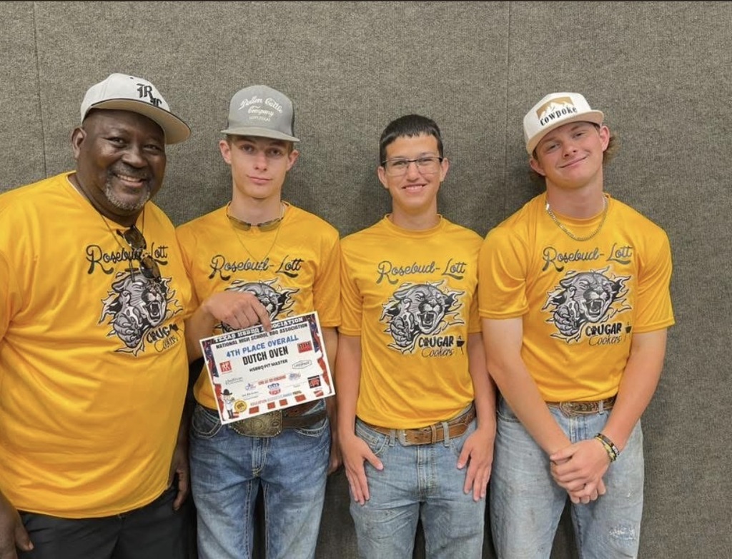 Four people in matching yellow "Rosebud-Lott Cougar" shirts stand proudly. One holds a "4th Place Overall Dutch Oven" certificate. They appear happy and accomplished.