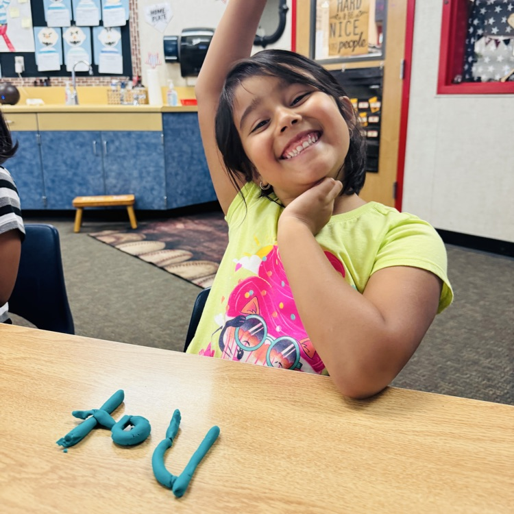 little girl raising her hand with word “not” shaped with Playdoh
