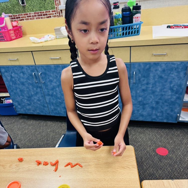 little girl shaping letter out of playdoh 