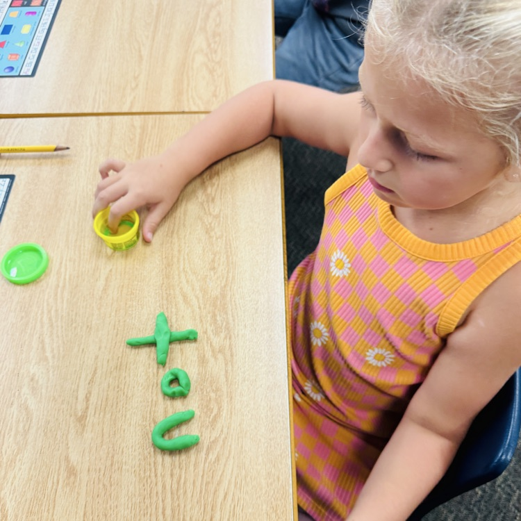 girl shaping the word “not” out of playdoh 