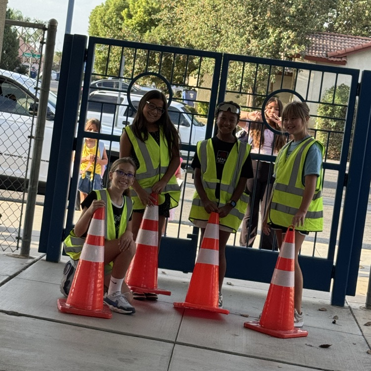 students wearing safety vests and holding red safety cones