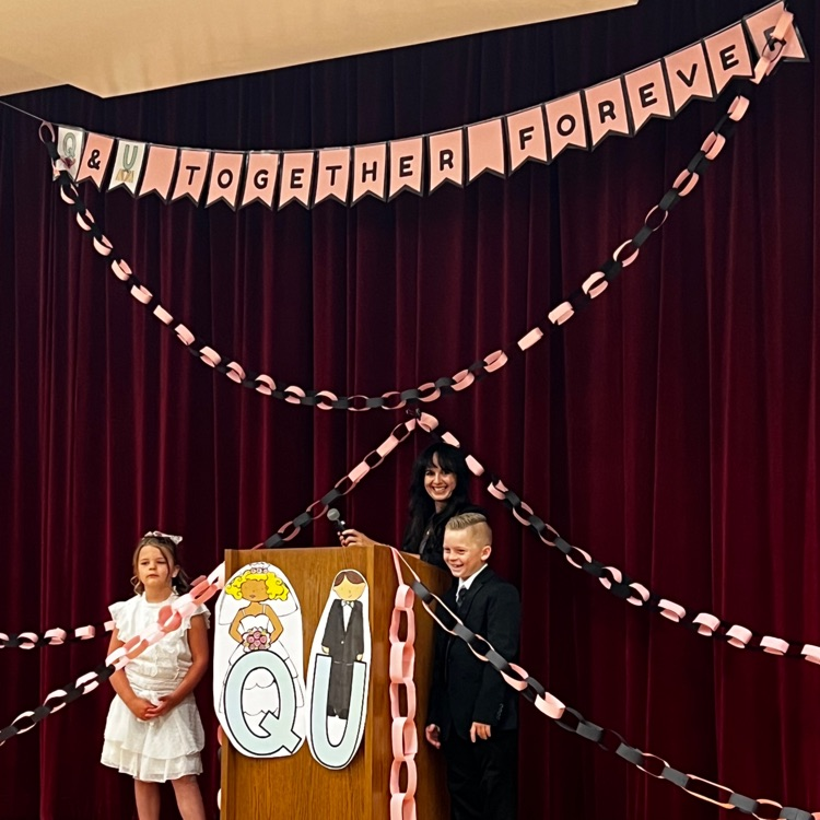 boy and girl dressed as bride and groom with banner sign “better together"