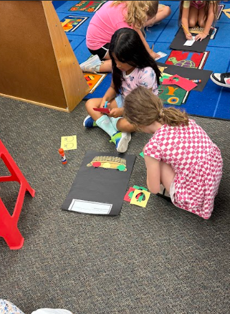 students cutting paper apples working on a math poster