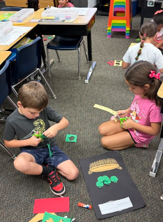 students cutting paper apples working on a math poster
